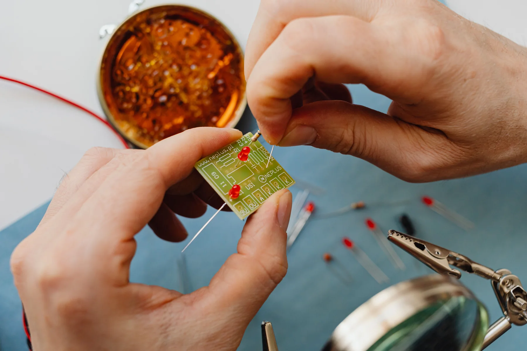 Hands fitting components to a printed circuit board; representative process photograph