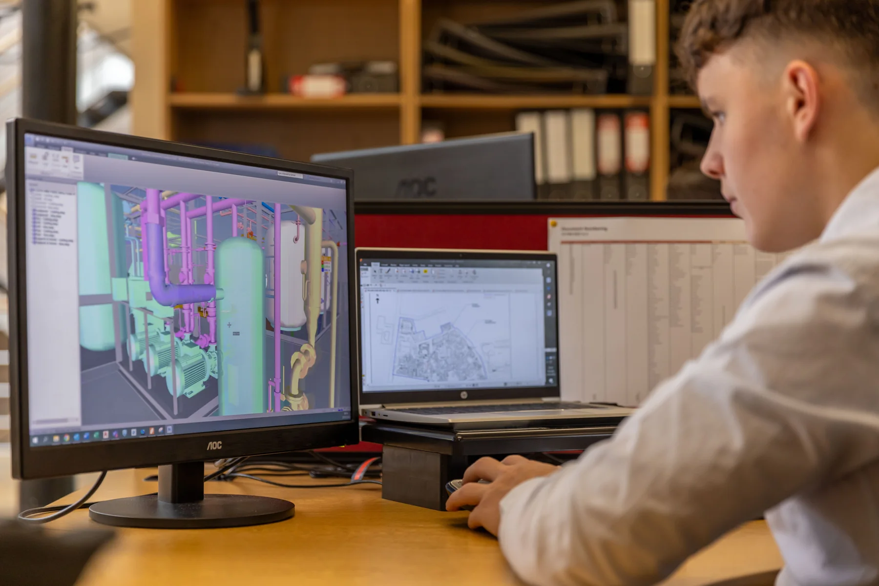 Engineer reviewing a CAD assembly on screen; representative process photograph